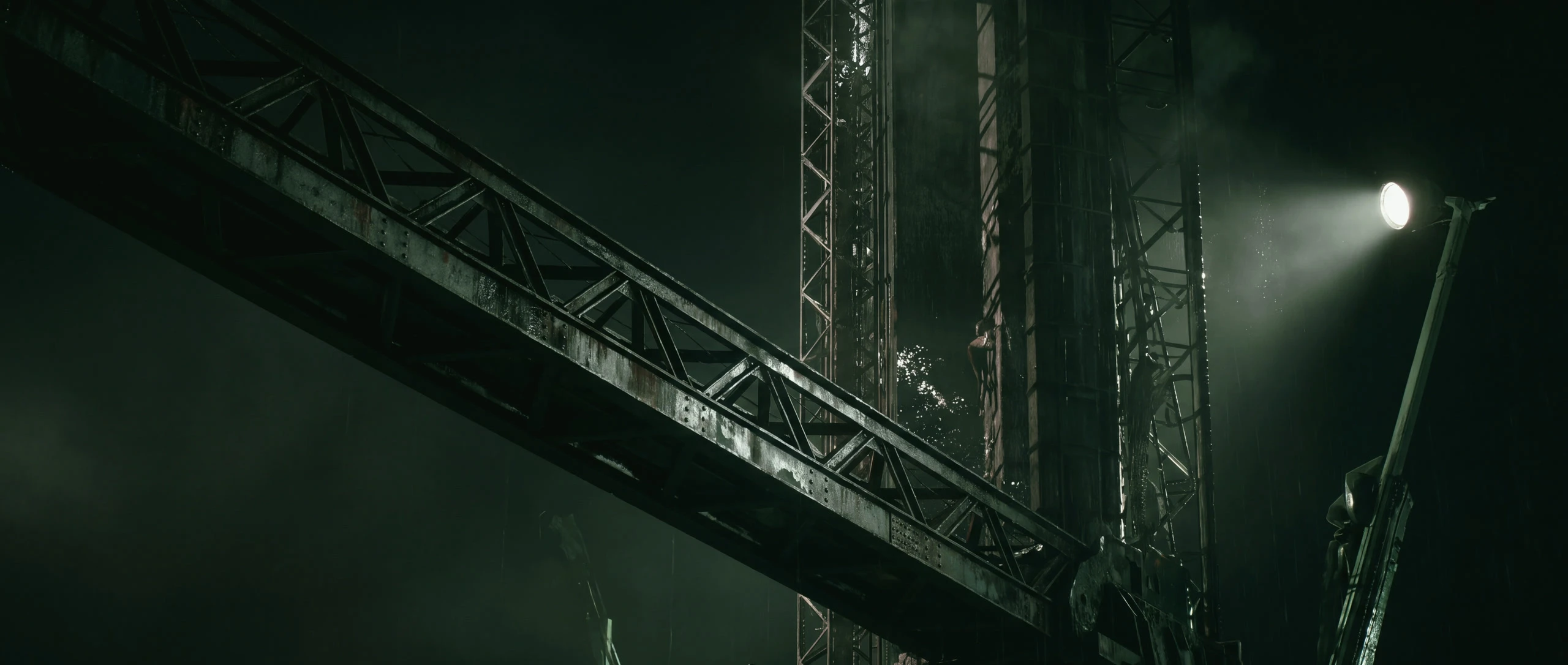 A latticed crane boom crossing a floodlit tower, seen from below at night