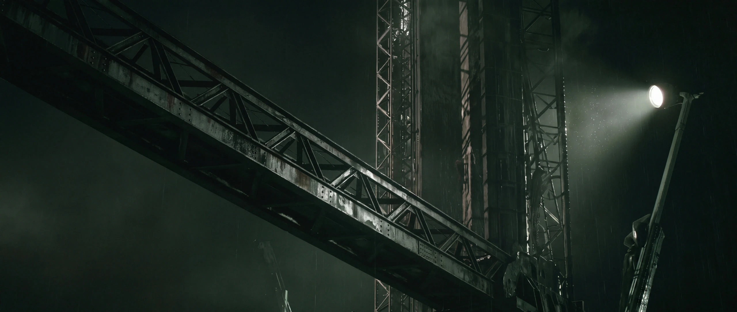 A latticed crane boom crossing a floodlit tower, seen from below at night