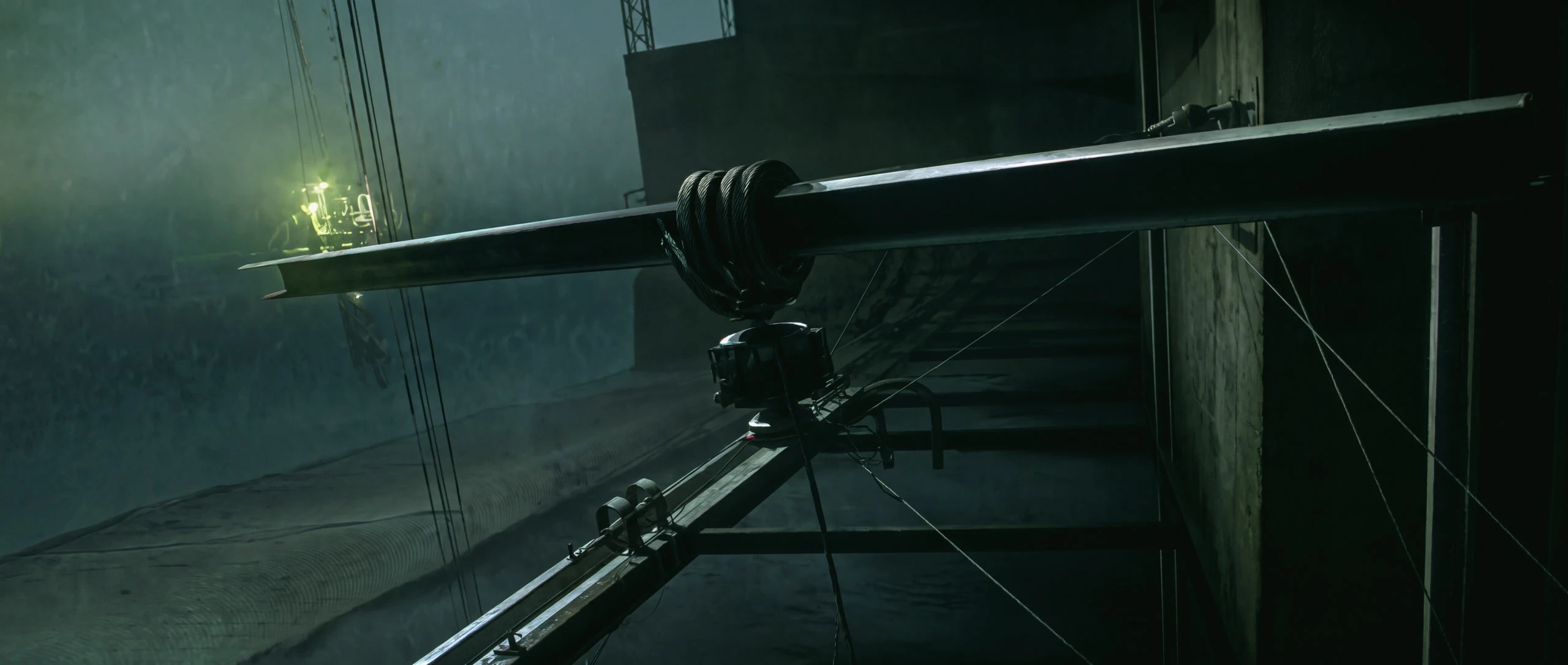 A steel beam hanging from a crane cable over a night site